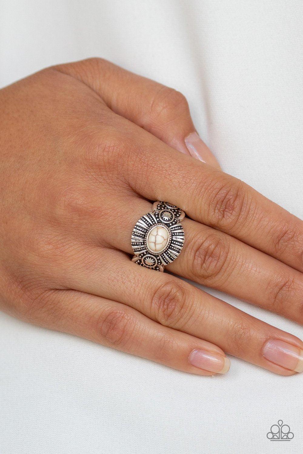 Paparazzi Accessories Thirst Quencher - White An oval white stone is pressed into the center of an ornate silver frame radiating with linear and sunburst patterns for a seasonal flair. Features a dainty stretchy band for a flexible fit. Sold as one indivi