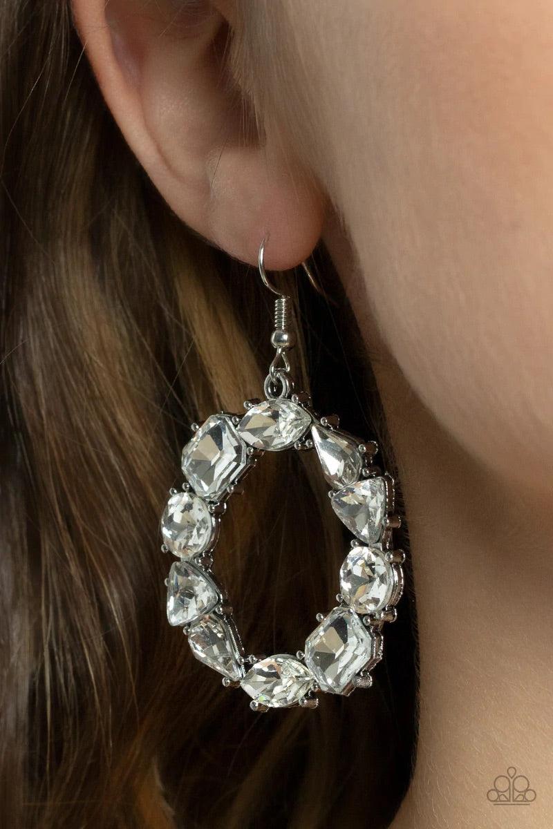 Paparazzi Accessories GLOWING In Circles - White Featuring glistening silver fittings, a regal assortment of round, triangular, teardrop, marquise, and emerald cut white rhinestones delicately coalesce into a jaw-dropping hoop. Earring attaches to a stand