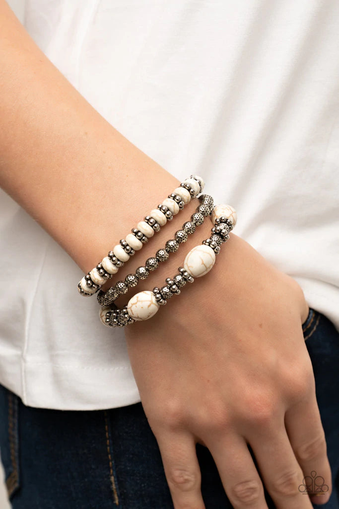 Paparazzi Accessories Take by SANDSTORM - White Infused with the refreshing allure of white beads, antiqued silver beads and studded accents are threaded along stretchy bands, creating a stack of artisan-inspired flair. Sold as one set of three bracelets.