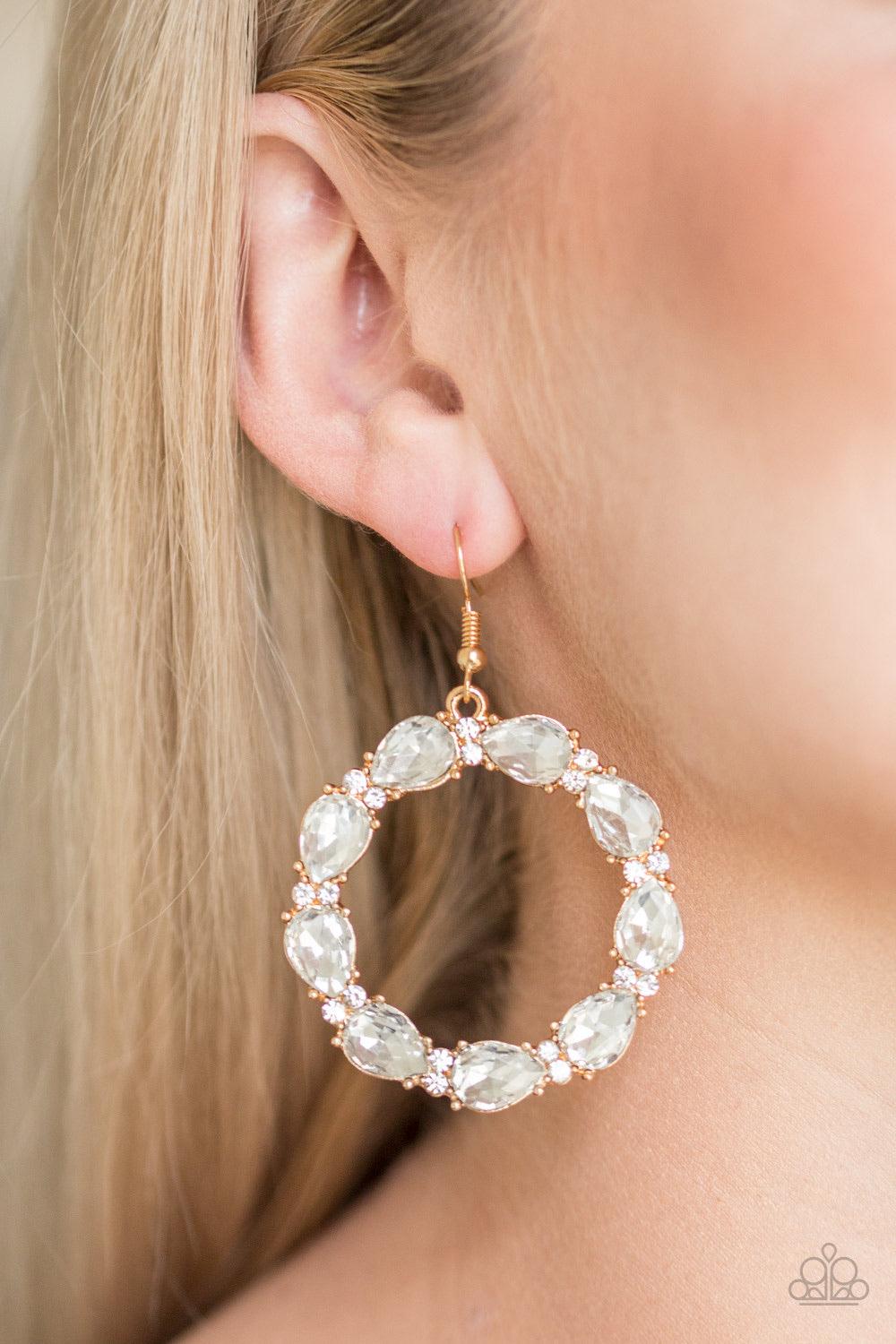 Paparazzi Accessories Ring Around The Rhinestones - Gold Glittery white rhinestones and white teardrop gems circle into a sparkling hoop for a glamorous look. Earring attaches to a standard fishhook fitting. Sold as one pair of earrings. Jewelry