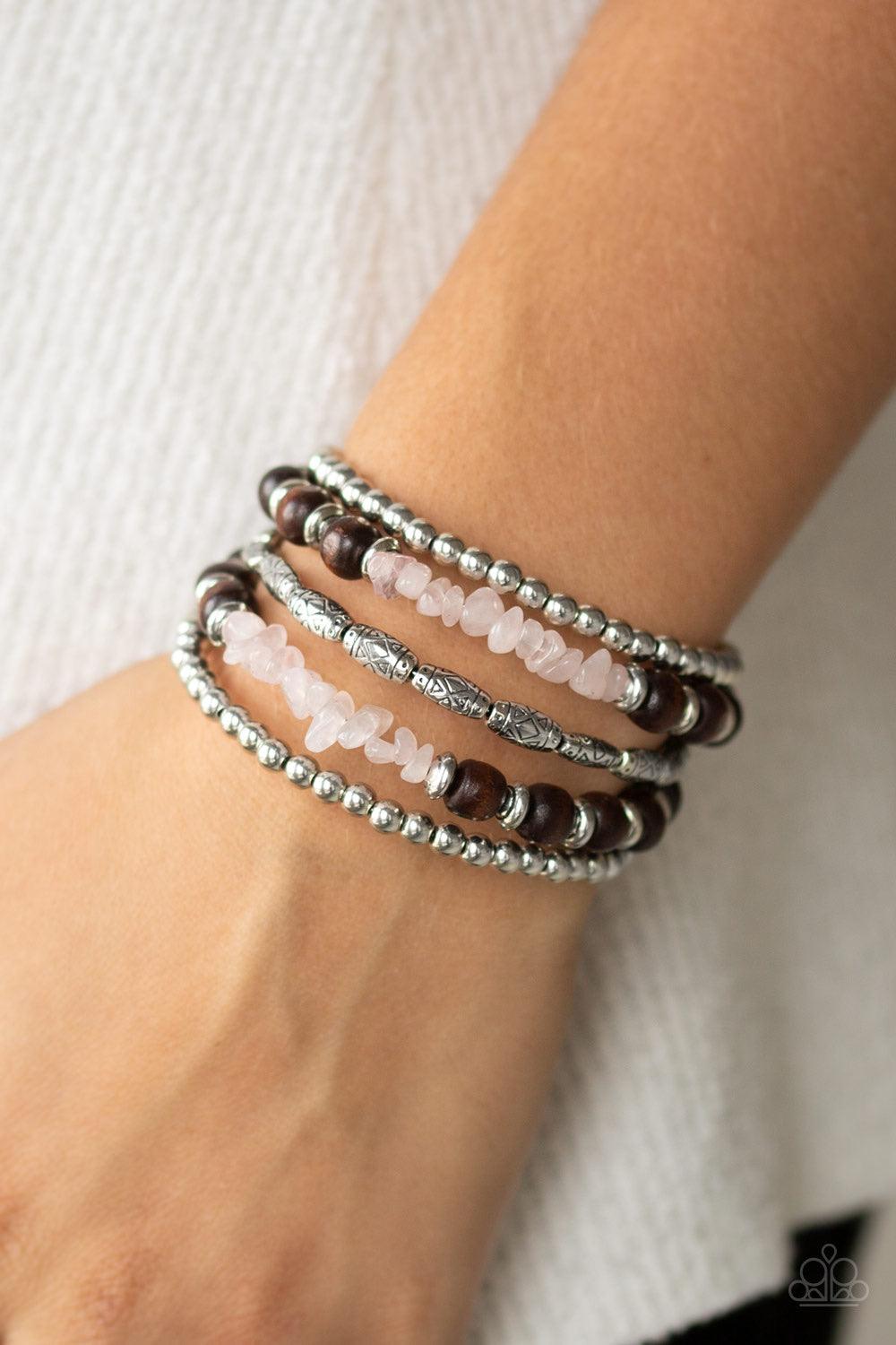 Paparazzi Accessories Soul Searchin - Pink A collection of shiny silver beads, glassy pink stones, wooden beads, and ornate silver accents are threaded along a coiled wire, creating an earthy infinity wrap style bracelet around the wrist. Jewelry