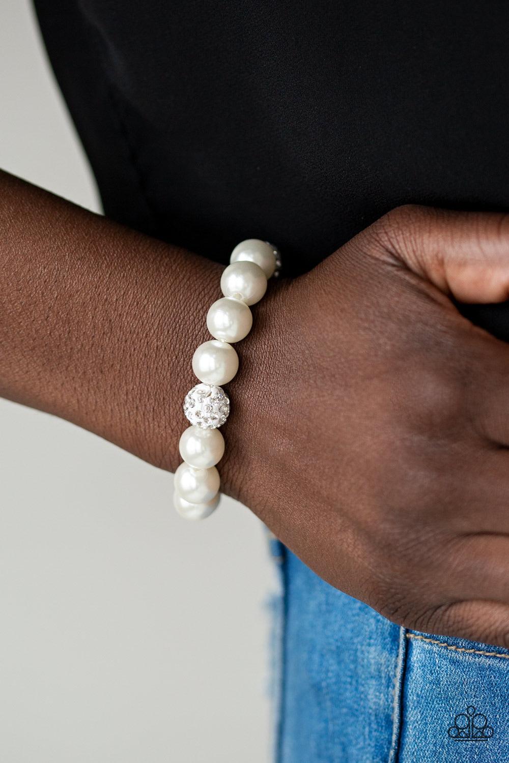 Paparazzi Accessories Cake Walk - White A collection of white pearls and white rhinestone encrusted beads are threaded along a stretchy band around the wrist for a refined flair. Sold as one individual bracelet. Jewelry