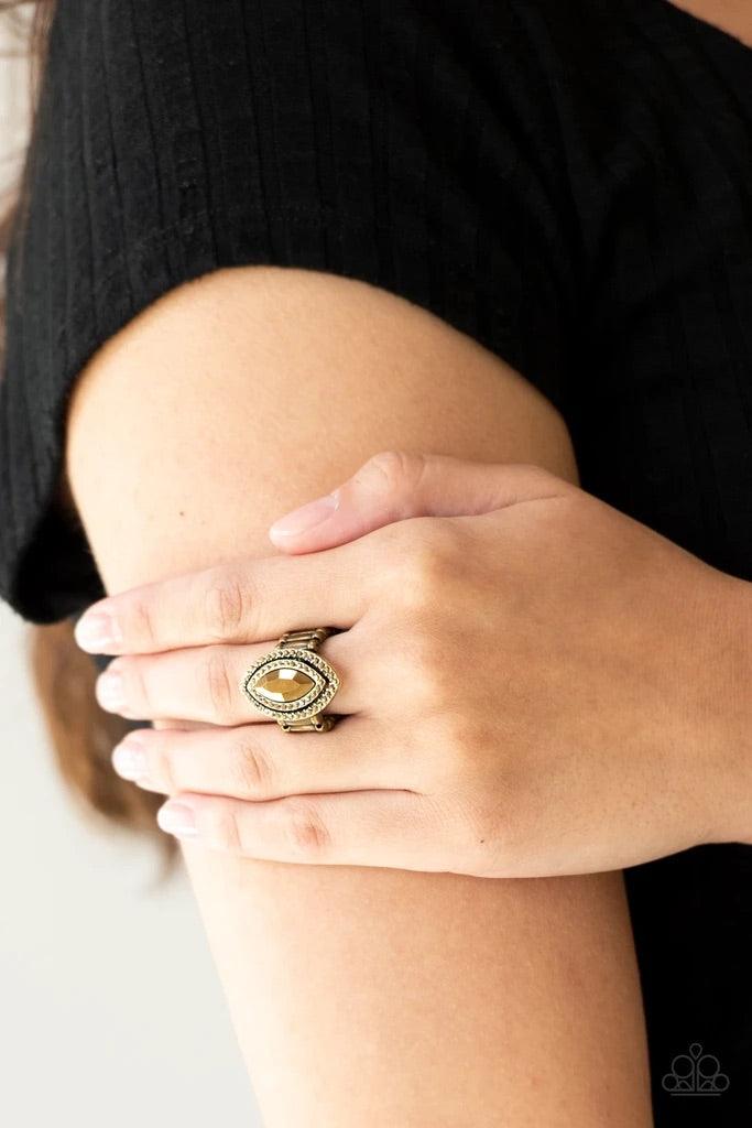 Paparazzi Accessories Modern Millionaire - Brass Featuring a regal marquise style cut, a golden aurum gem is pressed into the center of stacked brass frames radiating with glittery aurum rhinestones for a glamorous finish. Features a stretchy band for a f