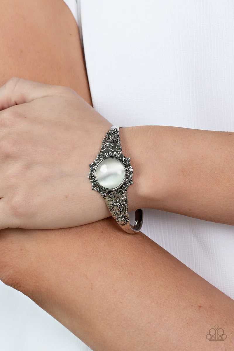 Paparazzi Accessories Extravagantly Enchanting - White A mystical white cat's eye stone is pressed into the floral center of a dainty silver cuff that is abloom with flowery details, creating an enchanting pop of color around the wrist. Sold as one indivi