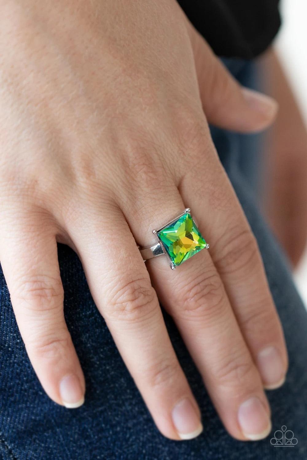 Paparazzi Accessories Ready For My Coronation- Green Featuring a stellar UV shimmer, an oversized princess cut rhinestone shines brilliantly atop a dainty silver band for a sparkly finish. Features a dainty stretchy band for a flexible fit. Sold as one in