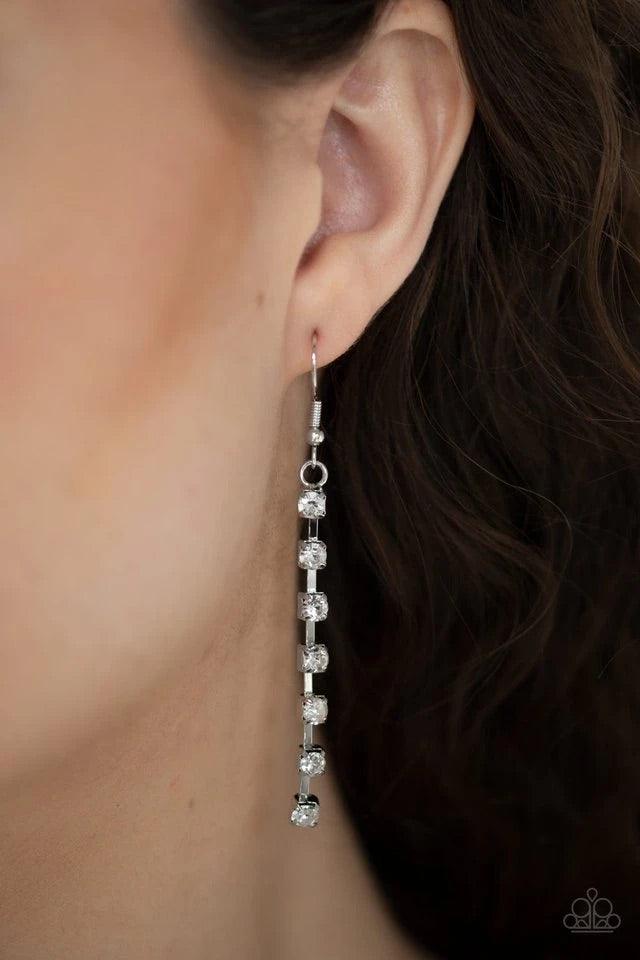Paparazzi Accessories Glitter Bomb - White Chains of glittery white rhinestones stream from the bottom of a bowing silver bar, creating a tapered fringe at the bottom of a lengthened silver chain. Features an adjustable clasp closure. Sold as one individu