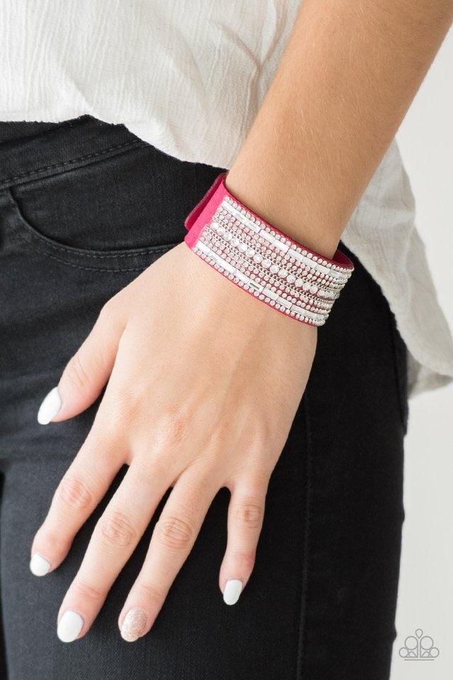 Paparazzi Accessories Rebel Radiance - Pink Featuring classic round and edgy emerald style cuts, glittery white rhinestones and glistening silver chains are encrusted along bands of pink suede for a sassy look. Features an adjustable snap closure. Sold as