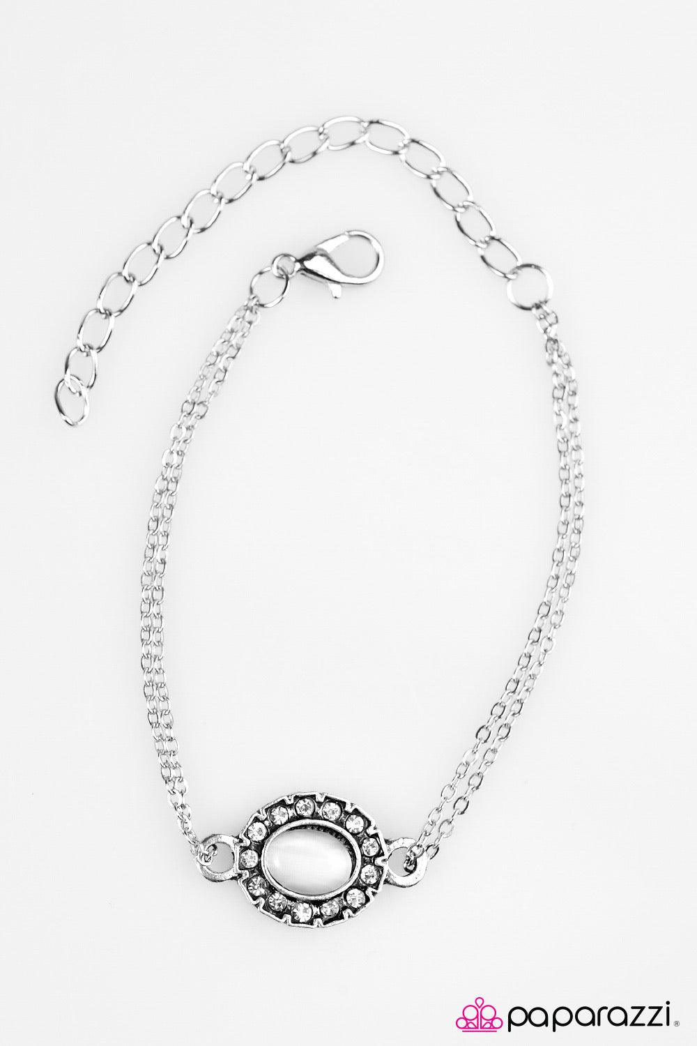 Paparazzi Accessories Moonlit Pools - White Dazzling white rhinestones spin around a white moonstone center, creating a whimsical pendant. Double strands of silver chain loop through the charm’s fittings, creating a stagnant pendant across the wrist. Feat
