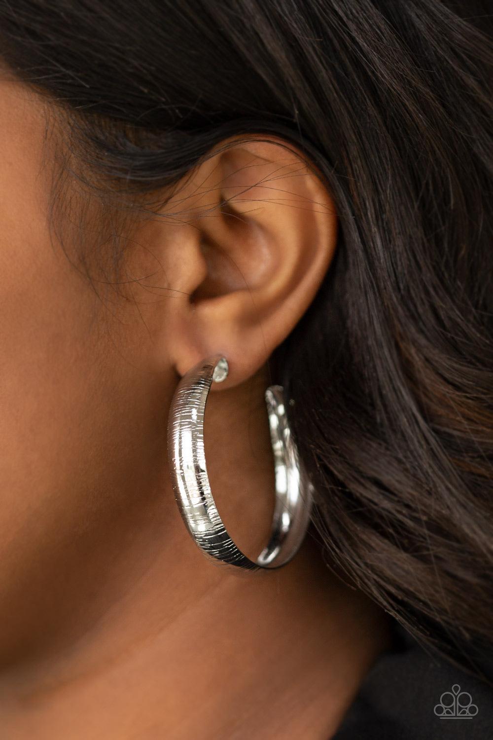 Paparazzi Accessories Hoop Wild - Silver Etched in a shimmery linear pattern, a thick silver hoop curls around the ear for some classic edge. Earring attaches to a standard post fitting. Hoop measures approximately 2" in diameter. Jewelry