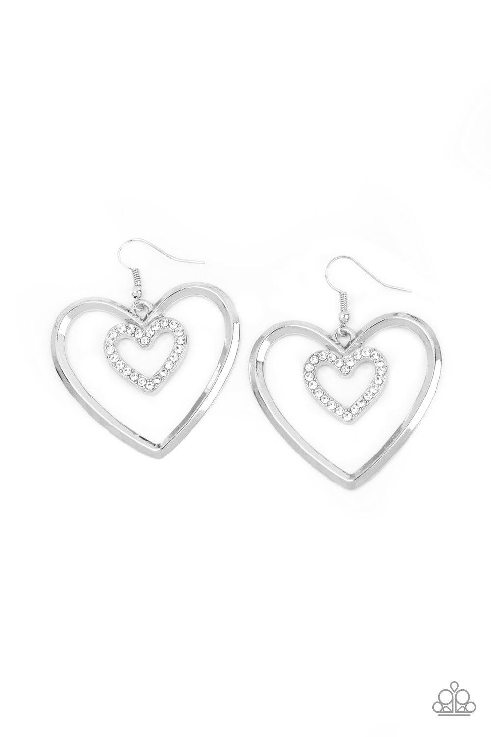 Paparazzi Accessories Heart Candy Couture - Silver A dainty white rhinestone encrusted heart frame swings from the top of an oversized silver heart frame, creating a charming duo. Earring attaches to a standard fishhook fitting. Jewelry