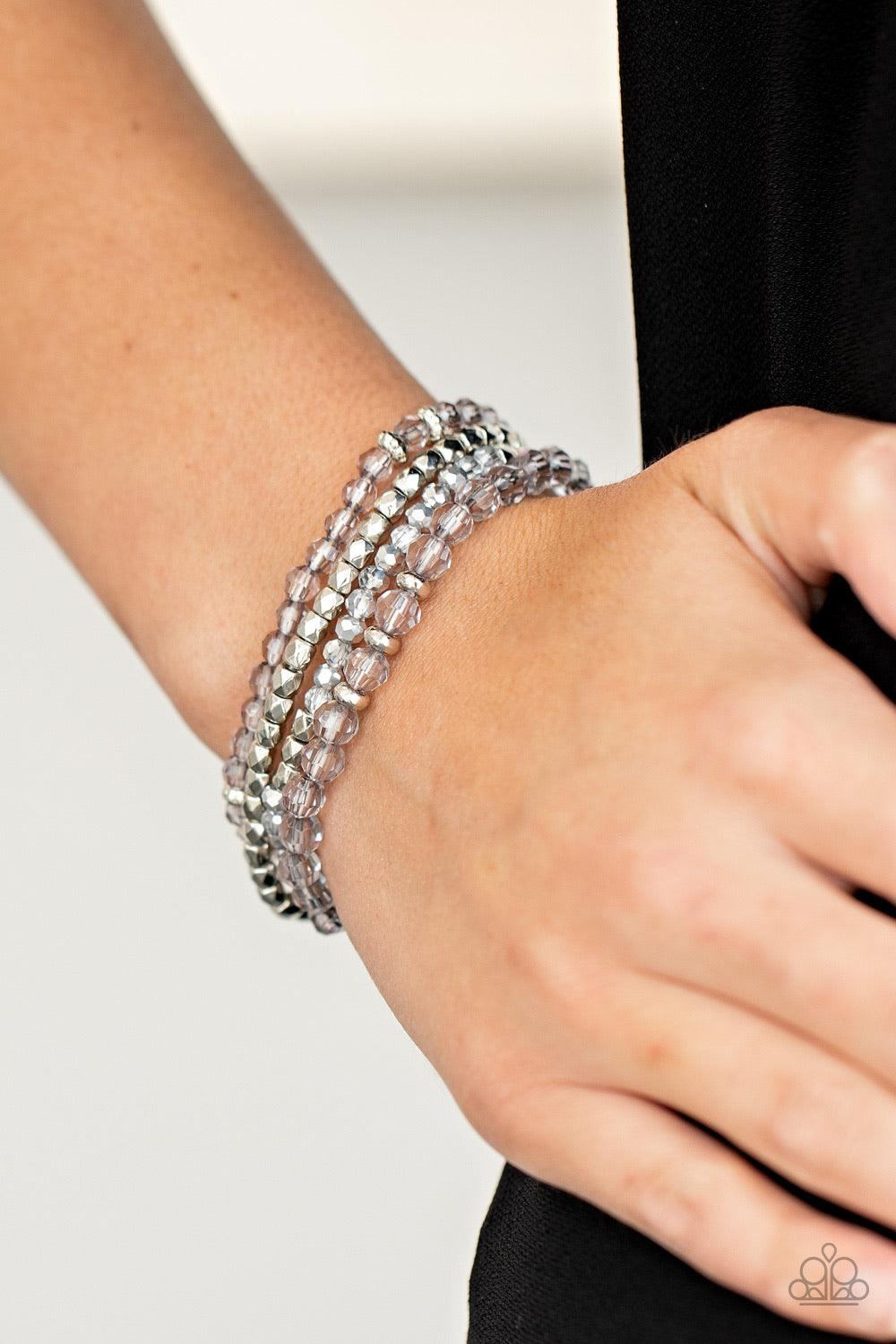 Paparazzi Accessories Crystal Crush - Silver A glittery collection of faceted silver beads and smoky and metallic flecked crystal-like beads are threaded along stretchy bands around the wrist, creating sparkly layers. Sold as one set of three bracelets. J