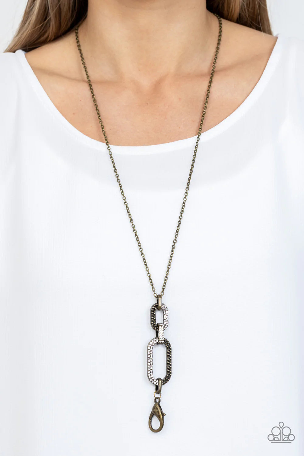 Paparazzi Accessories OVAL-Statement of the Year - Brass *Lanyard Featuring half studs and half white rhinestones, two sparkly brass oval frames link with rustic brass fittings at the bottom of a lengthened brass chain for a gritty-glamorous look. A lobst
