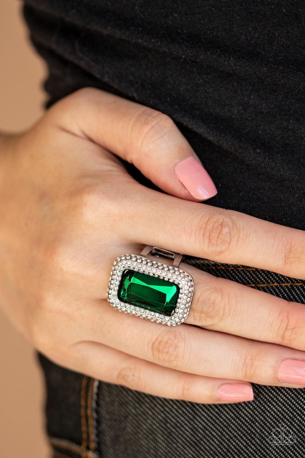 Paparazzi Accessories A Grand STATEMENT-MAKER - Green Featuring a regal emerald style cut, a dramatically oversized green rhinestone is nestled inside a silver frame encrusted in row after row of glassy white rhinestones for a blinding look. Features a st