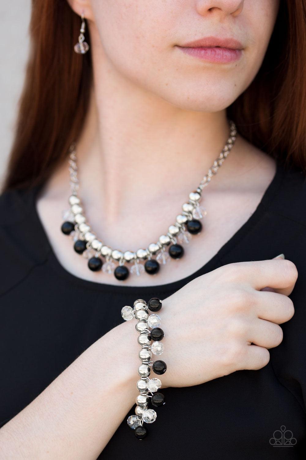 Paparazzi Accessories Power Trip - Black Infused with a bold silver chain, classic silver beads are threaded along a skinny wire below the collar. Polished black and faceted crystal-like beads swing from the bottom of the silver beads, creating a refined