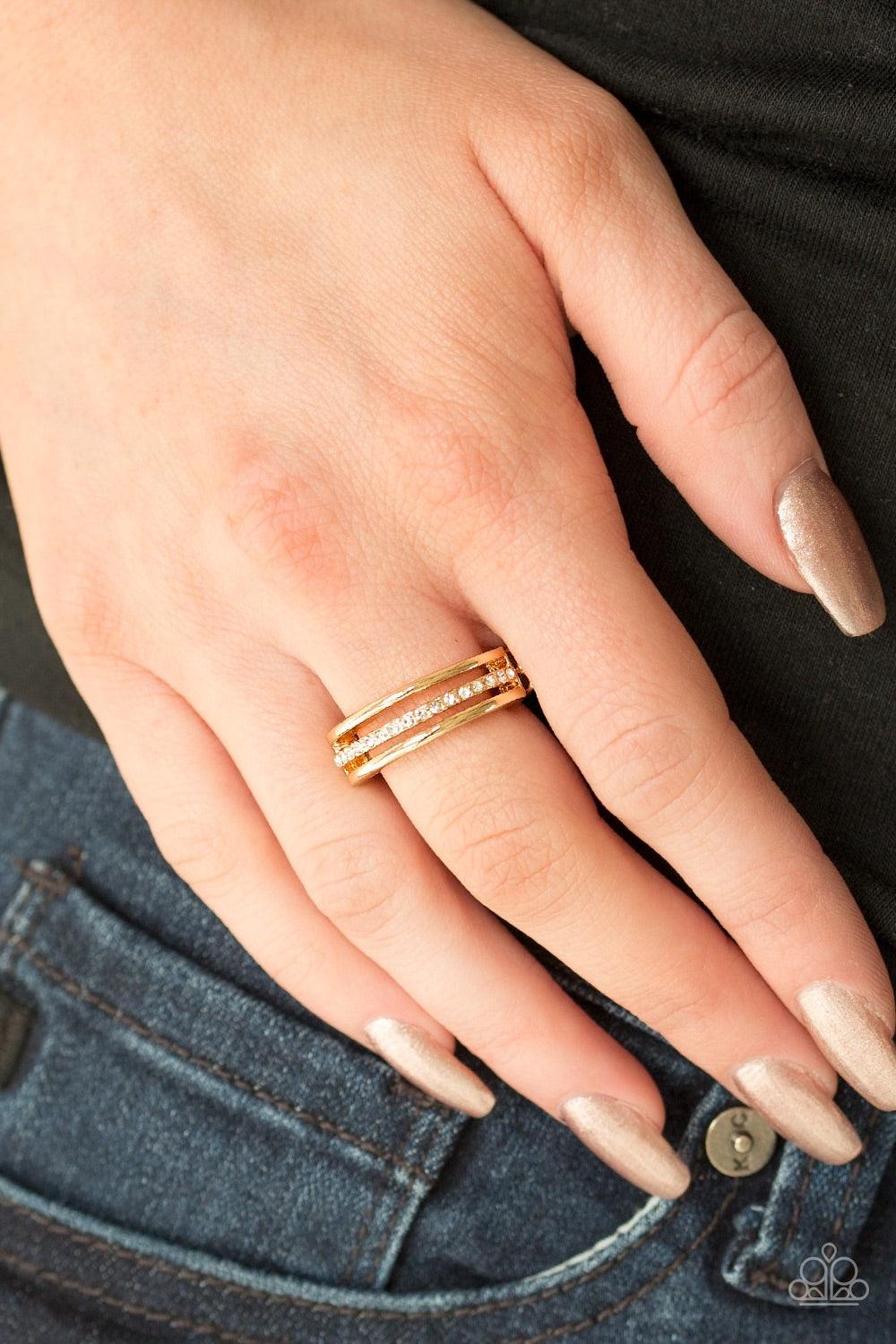 Paparazzi Accessories Center Court - Gold Dainty gold bands layer across the finger. The centermost band is encrusted in white rhinestones for a glamorous finish. Features a dainty stretchy band for a flexible fit. Jewelry