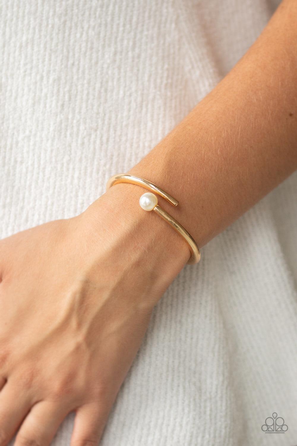 Paparazzi Accessories Industrial Impact ~Gold Featuring a solitaire white pearl, two shiny gold bars attach to a spring-like fitting as they curl around the wrist for a modern finish.