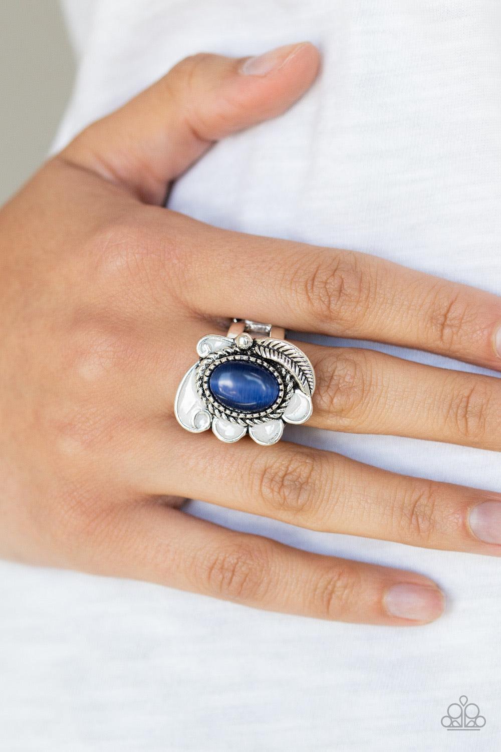 Paparazzi Accessories Fairytale Magic - Blue A glowing blue cat's eye stone is pressed into the center of a shimmery silver frame radiating with a silver feather and glistening white petals, creating a whimsical compilation atop the finger. Features a str