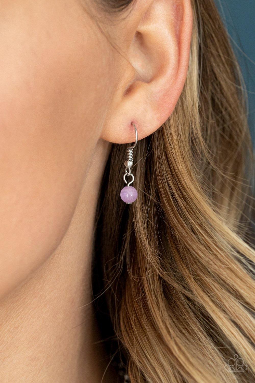 Paparazzi Accessories Fashion Flaunt - Purple Encrusted in rows of glassy white rhinestones, an imperfect silver teardrop frame is encrusted in a glowing purple cat's eye stone. The ethereal pendant swings from the bottom of a lengthened silver chain dott