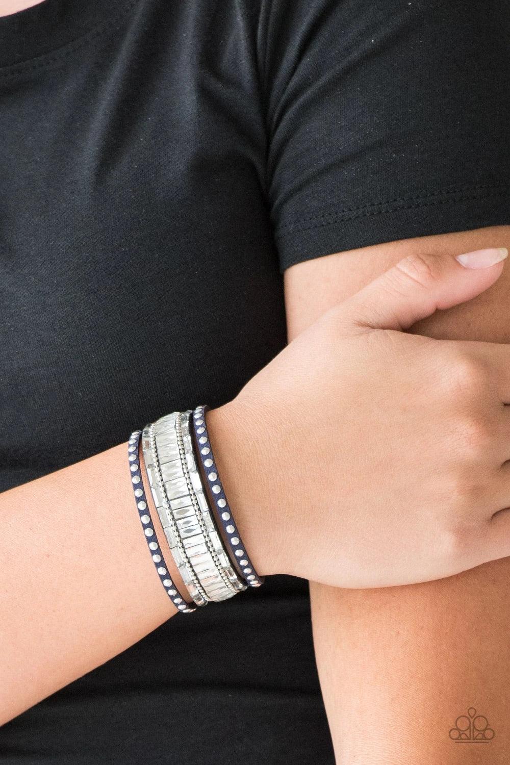 Paparazzi Accessories Rock Star Rocker - Blue Shiny silver studs, dainty silver ball chains, and edgy white emerald-cut rhinestones race along a spliced blue suede band for a rock star look. Features an adjustable snap closure. Sold as one individual brac