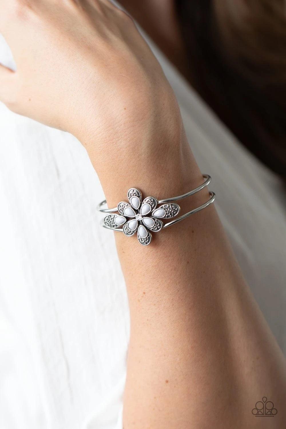Paparazzi Accessories Go With The FLORALS - Silver A collection of decorative silver petals topped with gray accents fans out around a dainty white rhinestone center, creating a whimsical floral frame that sits atop an airy silver cuff. Features a hinged