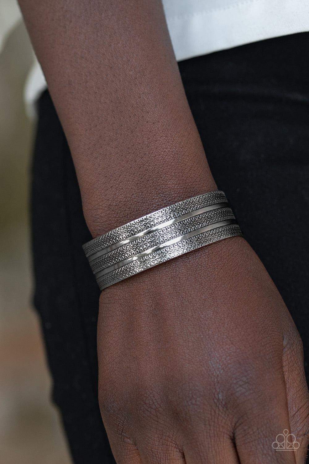 Paparazzi Accessories Patterned Plains - Silver Brushed in an antiqued shimmer, flat silver ribbons race across a silver cuff embossed in tactile textures for a tribal inspired flair. Sold as one individual bracelet. Jewelry