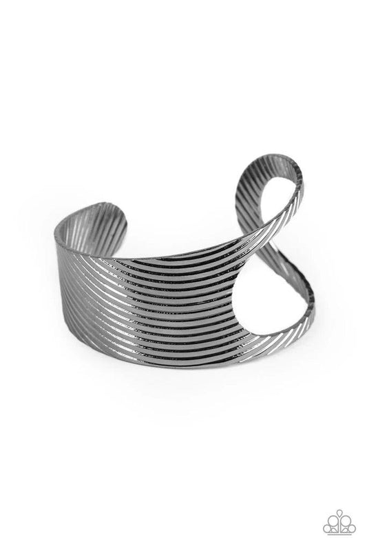 Paparazzi Accessories What GLEAMS Are Made Of - Black Stamped in a slanted linear pattern, a glistening gunmetal cuff featuring an airy asymmetrical cutout wraps around the cuff for a bold industrial look. Sold as one individual. Jewelry