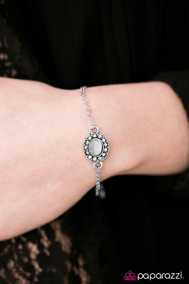 Paparazzi Accessories Moonlit Pools - White Dazzling white rhinestones spin around a white moonstone center, creating a whimsical pendant. Double strands of silver chain loop through the charm’s fittings, creating a stagnant pendant across the wrist. Feat