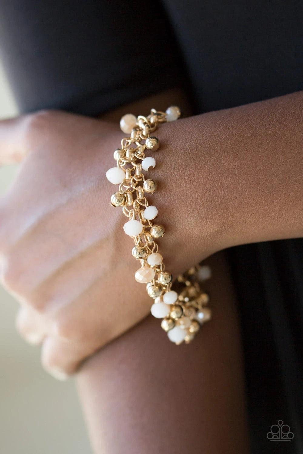 Paparazzi Accessories Just For The FUND Of It! - Gold Dipped into a golden metallic shimmer, faceted white beads and classic gold beads swing from interlocking gold chains, creating a refined fringe around the wrist. Features an adjustable clasp closure.
