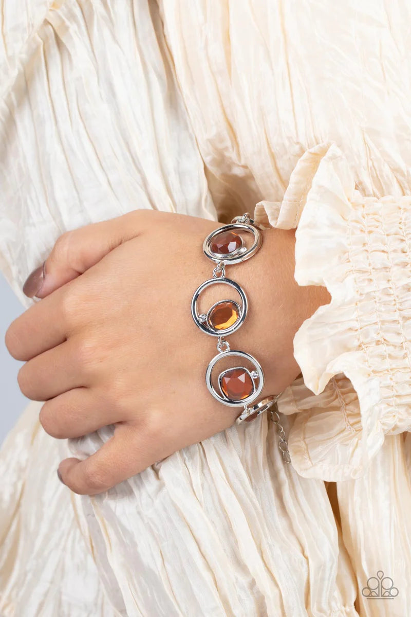 Paparazzi Accessories Date Night Drama - Brown Sporadically infused with dainty white rhinestones, a glittery collection of round, teardrop, and emerald cut topaz rhinestones haphazardly adorn the centers of interlocking silver hoops around the wrist for