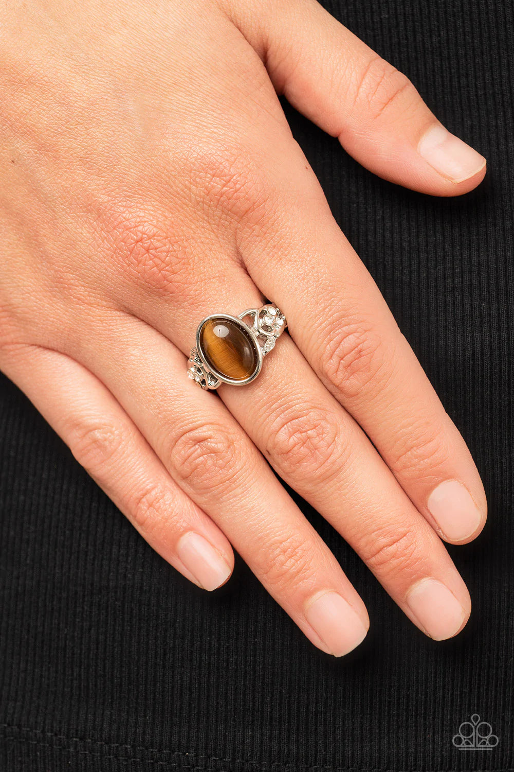 Paparazzi Accessories Crystals and Cat’s Eye - Brown An oval brown cat's eye stone adorns the center of a sleek silver fitting atop a band of braided silver bands timelessly dusted in dainty white rhinestones. Features a dainty stretchy band for a flexibl