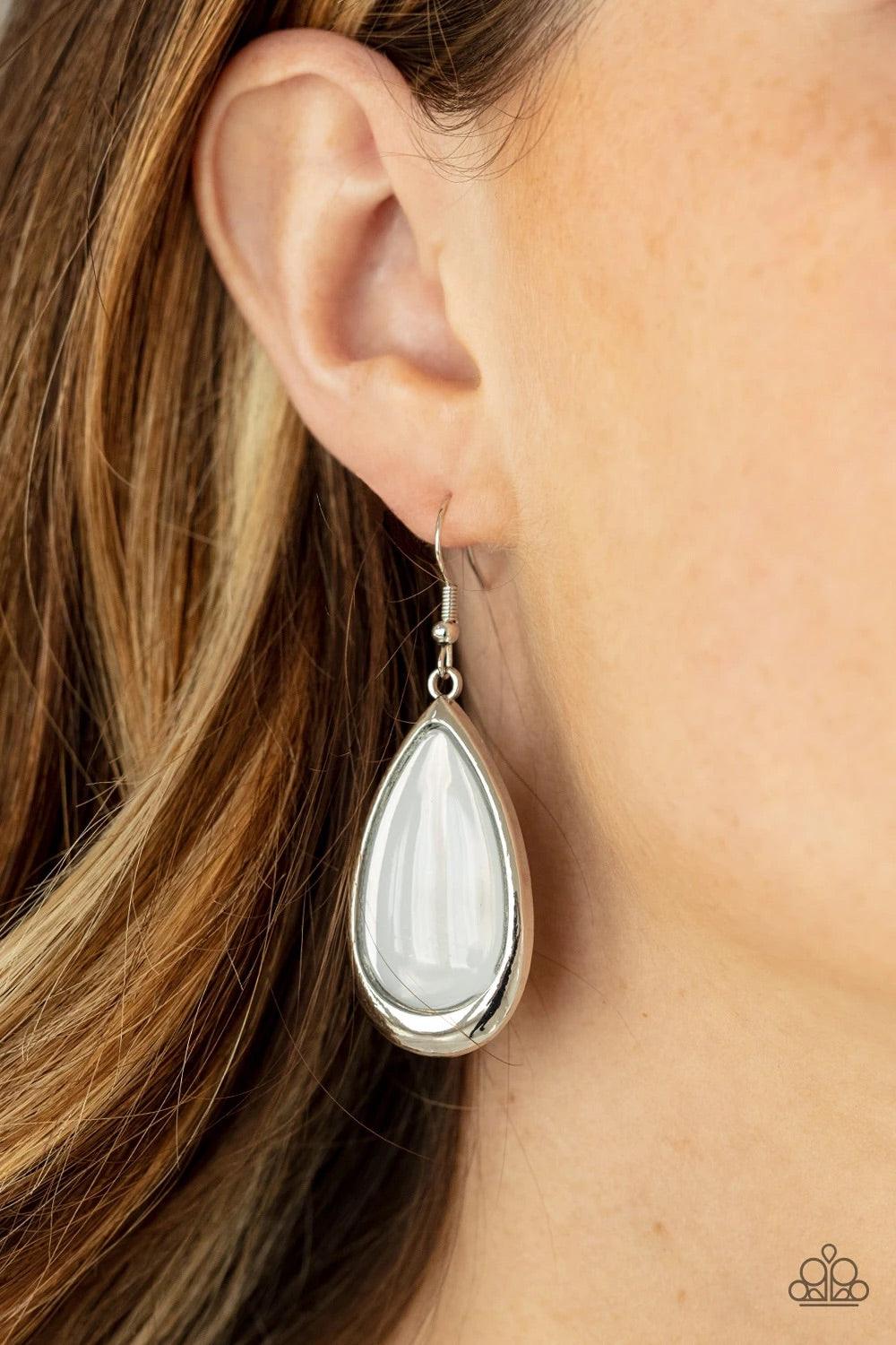 Paparazzi Accessories A World To Seer - White A glassy white teardrop is nestled inside a glistening silver frame, creating an ethereally elegant lure. Earring attaches to a standard fishhook fitting. Sold as one pair of earrings. Jewelry