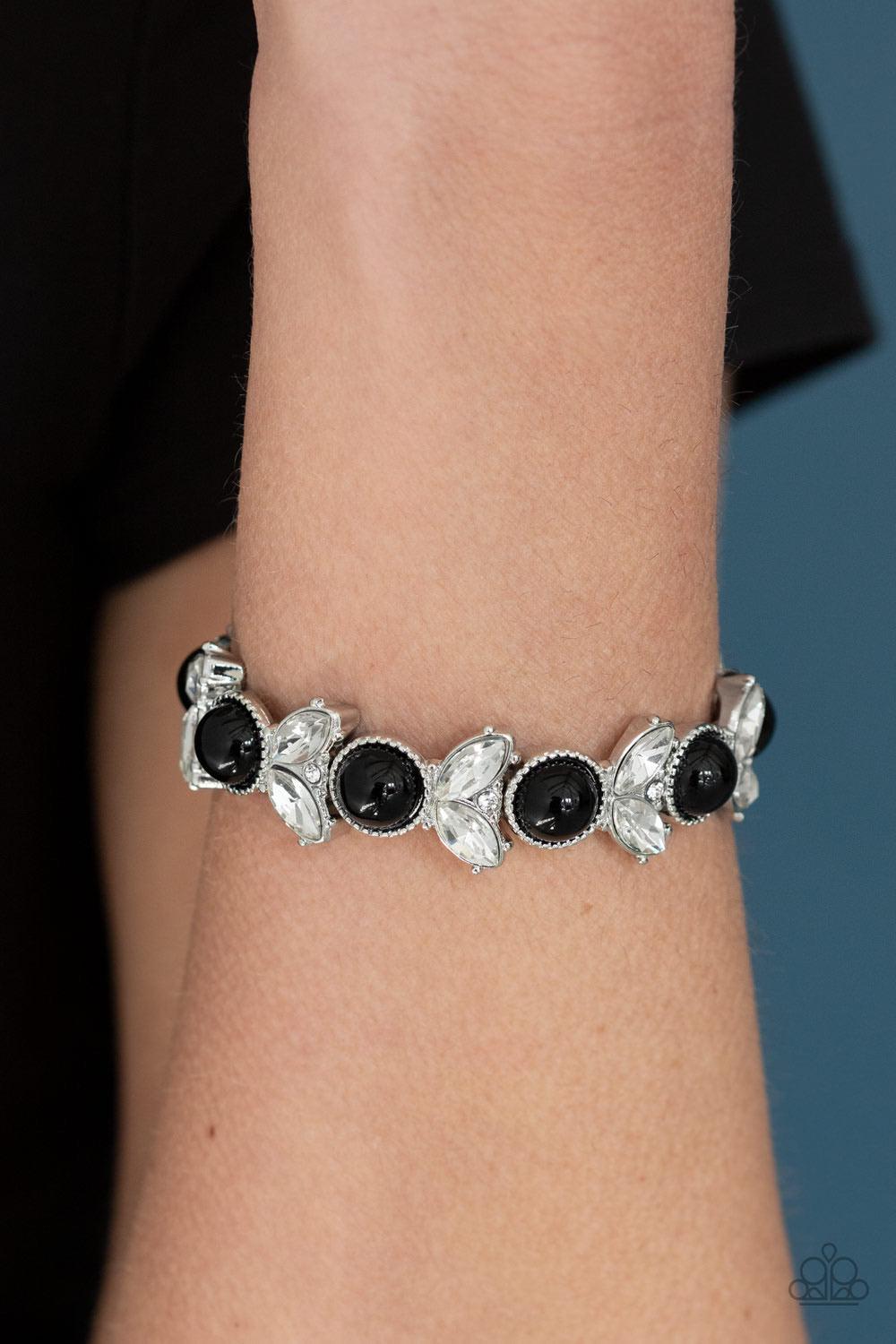 Paparazzi Accessories Opulent Oasis - Black Encrusted in dazzling white rhinestones and an oversized black bead, leafy silver frames are threaded along stretchy bands around the wrist for a timeless look. Sold as one individual bracelet. Jewelry