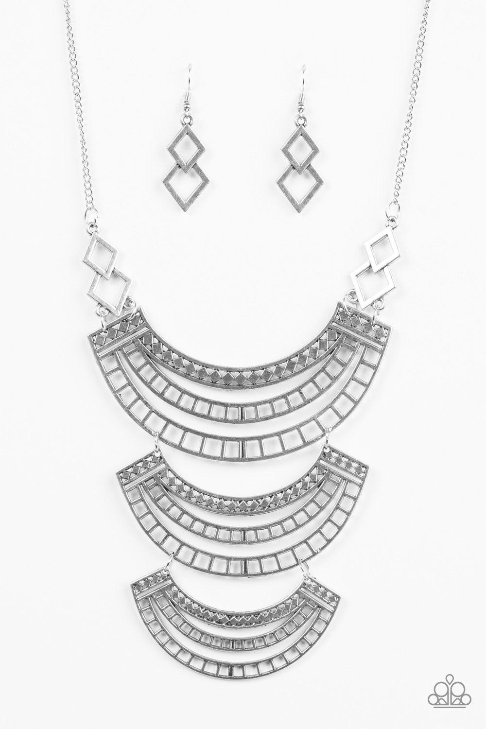 Paparazzi Accessories Queen Of The Nile - Silver Airy silver plates layer into a stunning indigenous display. Brushed in an antiqued shimmer, the eye-catching plates feature an intricate geometrical pattern for a bold tribal style. Features an adjustable