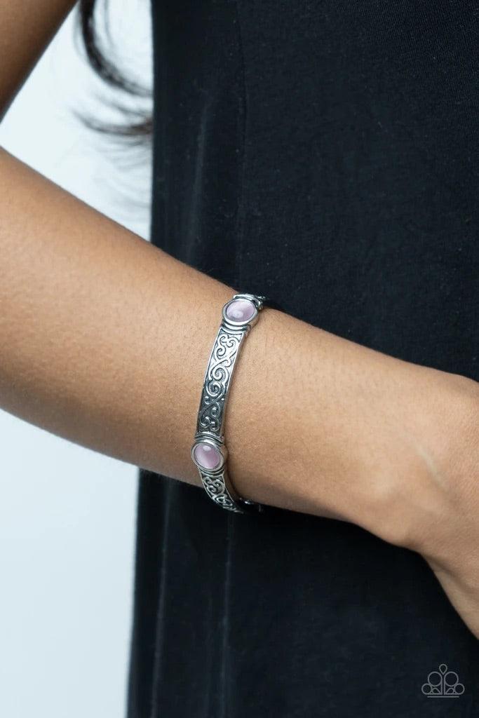 Paparazzi Accessories Ethereally Enchanting -Pink A pink cat's eye stone is pressed into a round frame at the end of a silver bar. Embossed with a whimsical vine motif, the patterned bars are threaded on stretchy bands to repeat around the wrist for an en