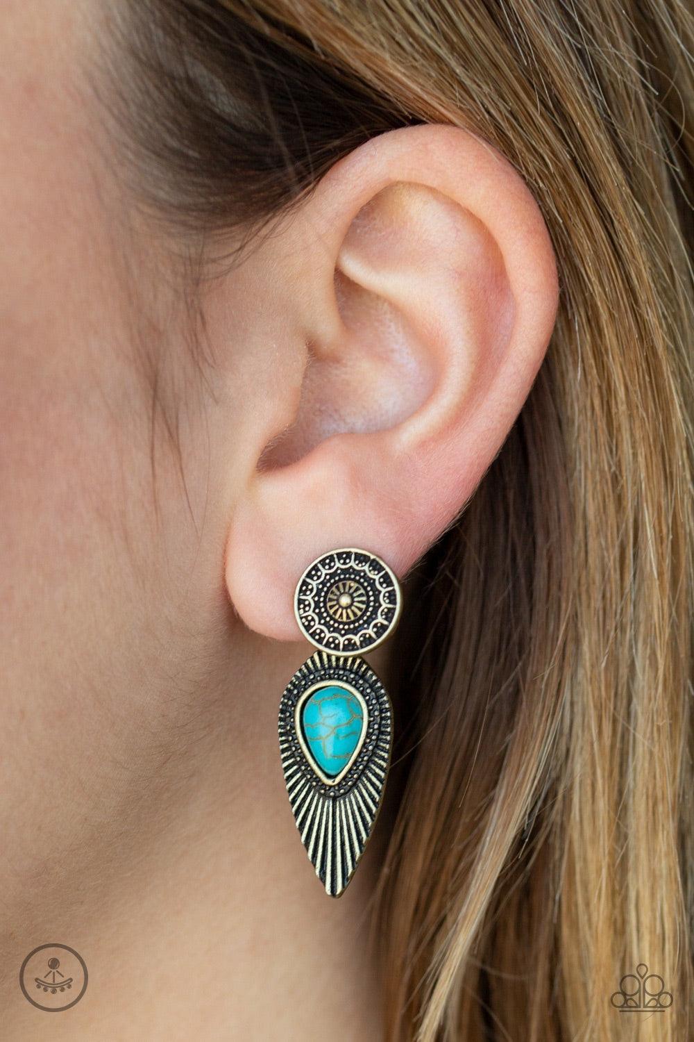 Paparazzi Accessories Fly Into The Sun - Brass An ornate brass disc attaches to a double-sided post, designed to fasten behind the ear. Dotted with a turquoise stone center, the feathery double-sided post peeks out beneath the ear for a bold artisan look.