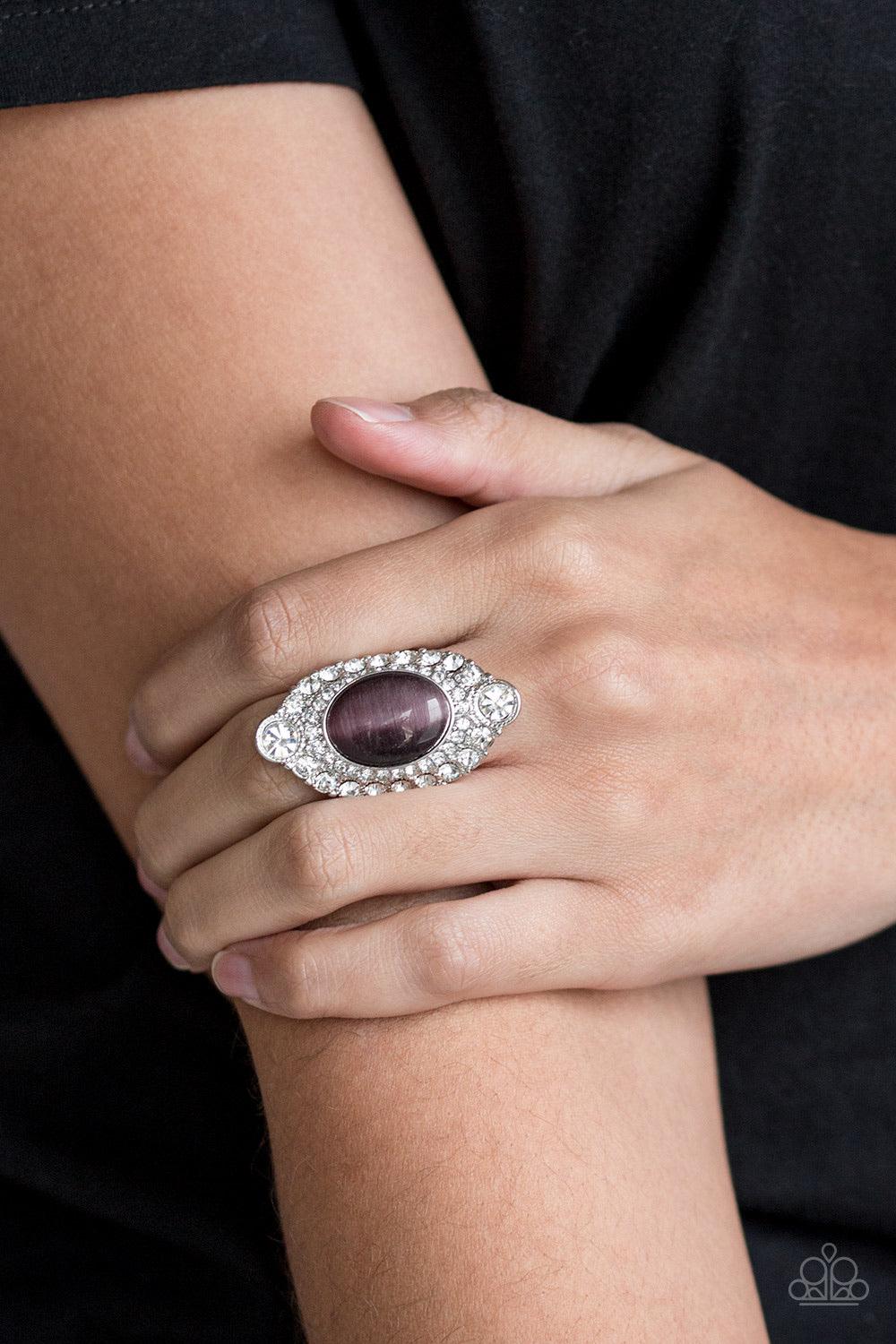 Paparazzi Accessories Riviera Royalty - Purple A glowing purple moonstone is pressed into a dramatic silver band radiating with glassy white rhinestones for a glamorous flair. Features a stretchy band for a flexible fit. Sold as one individual ring. Jewel