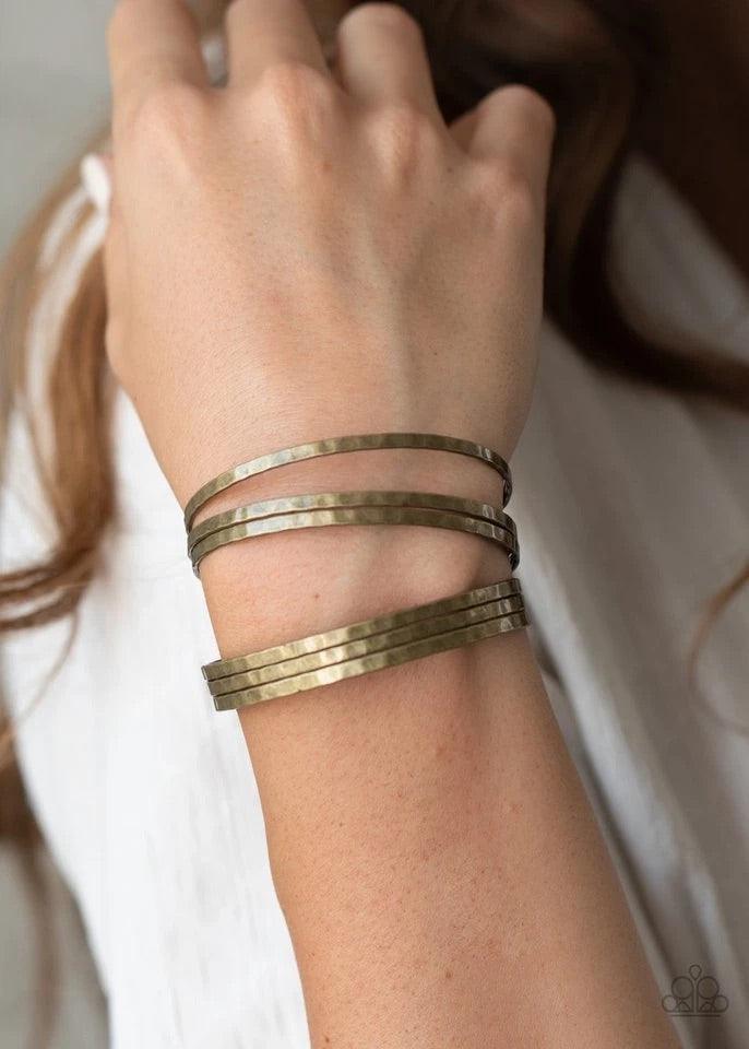 Paparazzi Accessories BAUBLE-Headed - Brass Brushed in an antiqued shimmer, hammered brass bars arc across the wrist. The flattened bars connect to two rod fittings, creating a trendy layered cuff. Sold as one individual bracelet. Jewelry