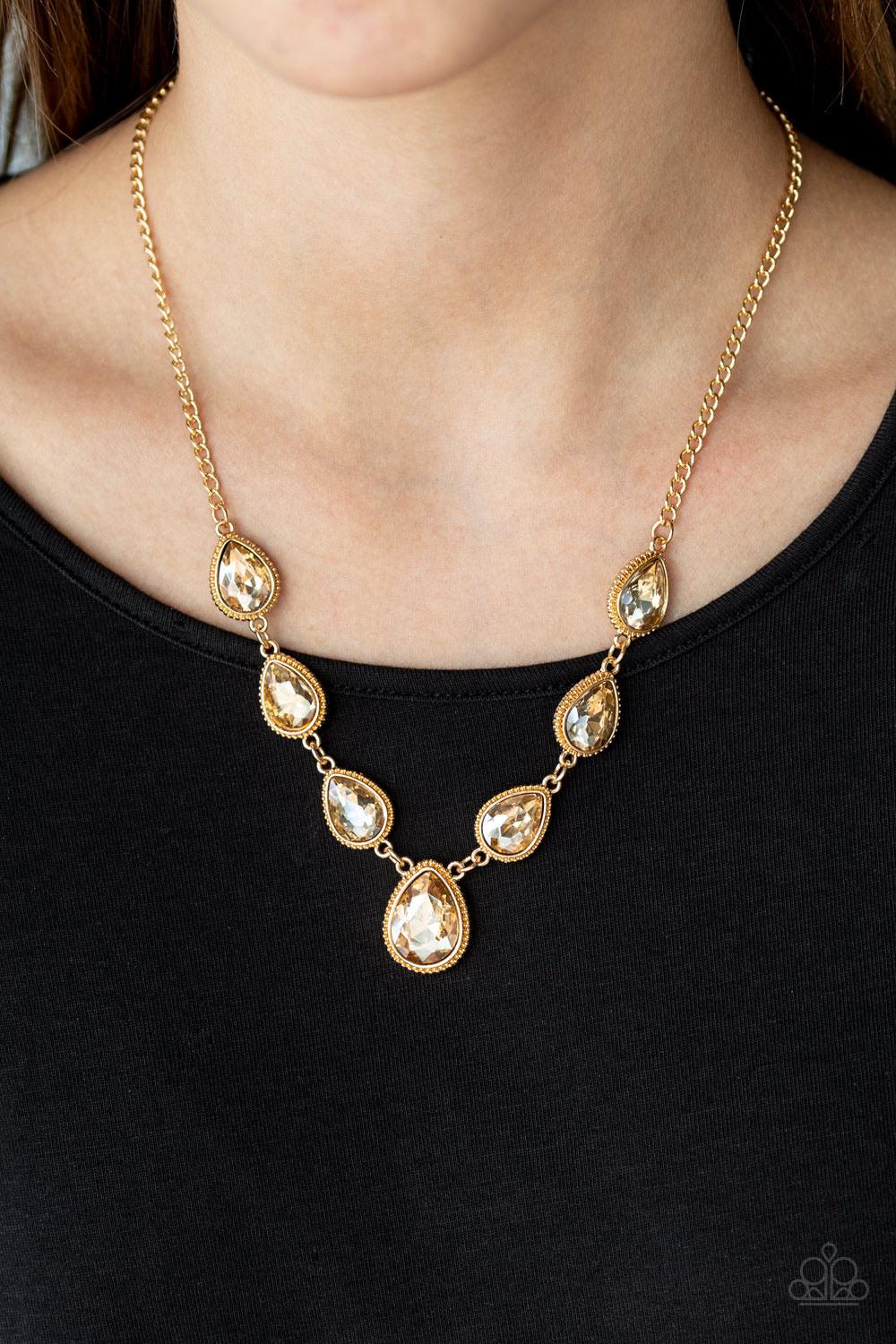 Paparazzi Accessories Socialite Social - Gold Featuring ornate gold frames, golden teardrop gems link below the collar in a timeless fashion. The largest teardrop swings from the center, creating a glamorous pendant. Features an adjustable clasp closure.