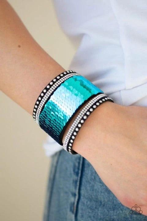 Paparazzi Accessories Heads Or MERMAID Trails - Blue Three aurum emerald-cut rhinestones are encrusted along three brass bands radiating with smooth surfaces and sections of glittery aurum rhinestones for an edgy fashion. Features a stretchy band for a fl