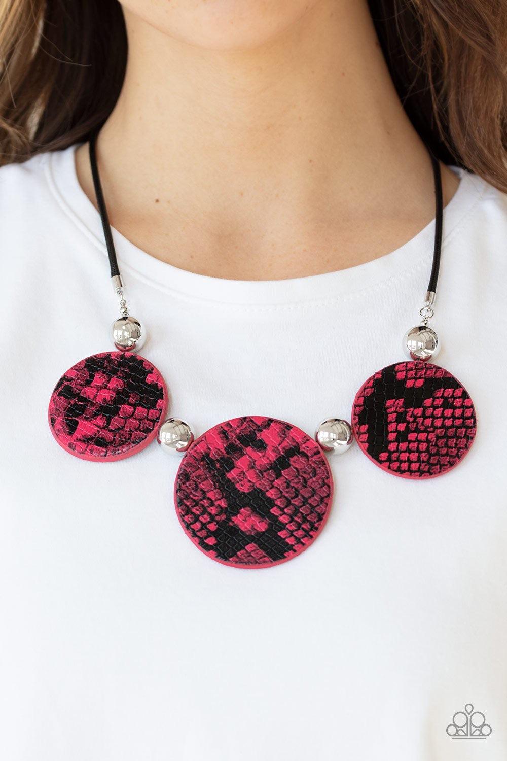 Paparazzi Accessories Viper Pit - Pink A wild collection of oversized silver beads and black and pink python patterned leather pieces are strung along an invisible wire below the collar for statement-making finish. Features an adjustable clasp closure. So