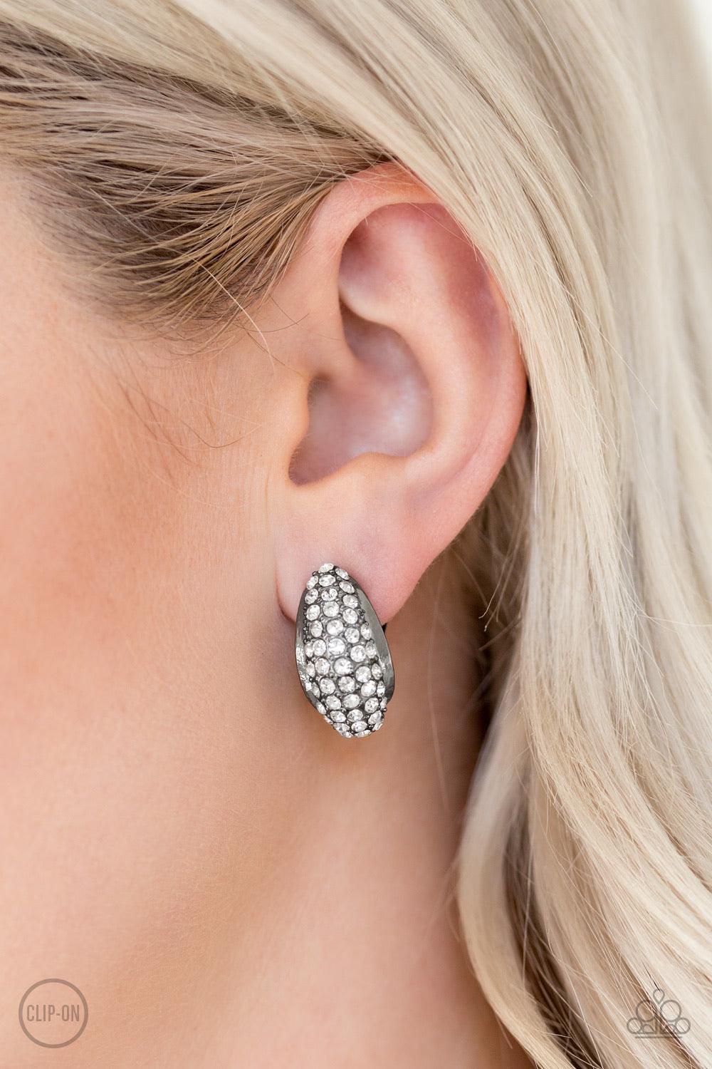 Paparazzi Accessories Revenue Avenue - Black *Clip-On A glistening gunmetal frame is encrusted in row after row of glassy white rhinestones for a timeless look. Earring attaches to a standard clip-on fitting. Jewelry