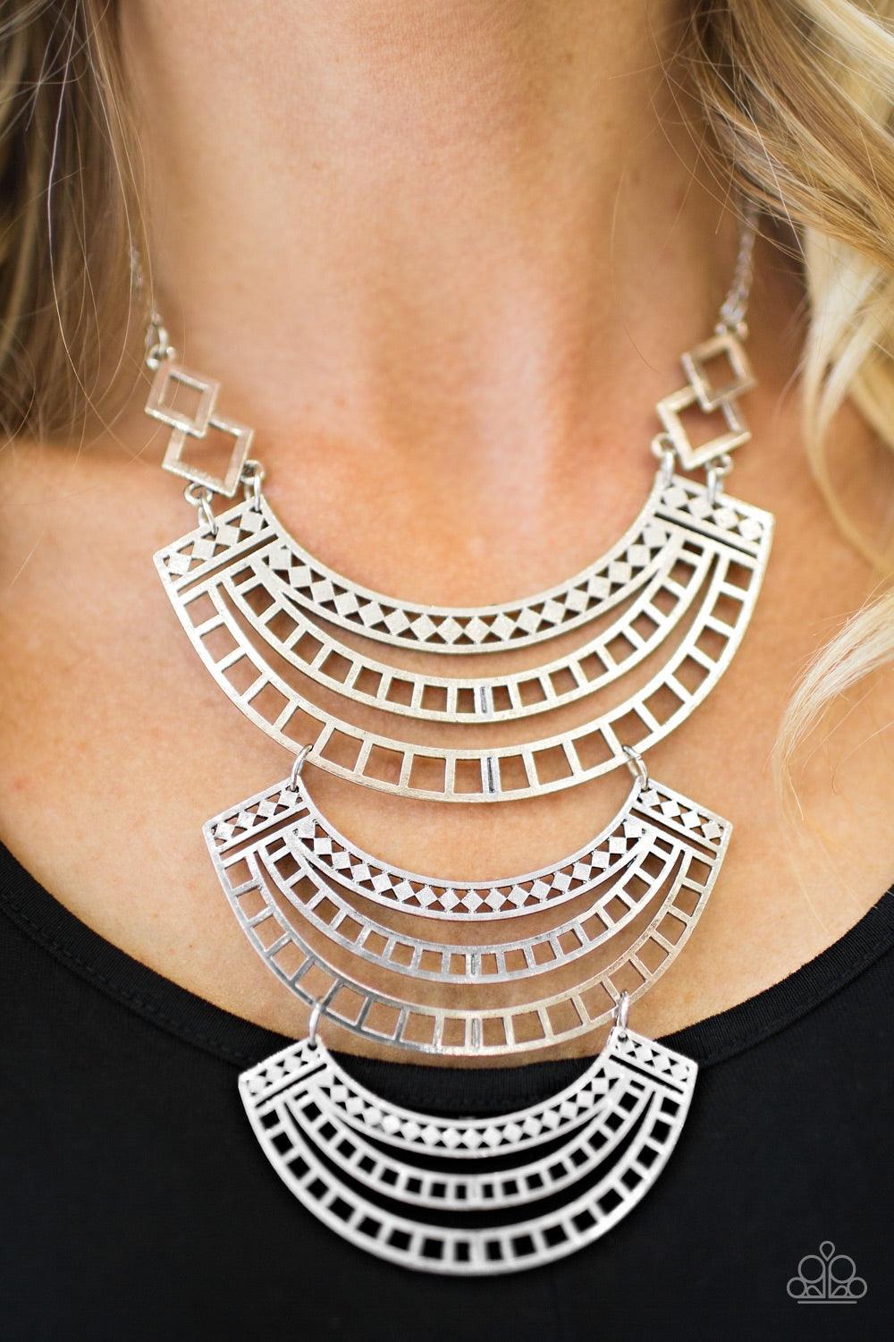 Paparazzi Accessories Queen Of The Nile - Silver Airy silver plates layer into a stunning indigenous display. Brushed in an antiqued shimmer, the eye-catching plates feature an intricate geometrical pattern for a bold tribal style. Features an adjustable