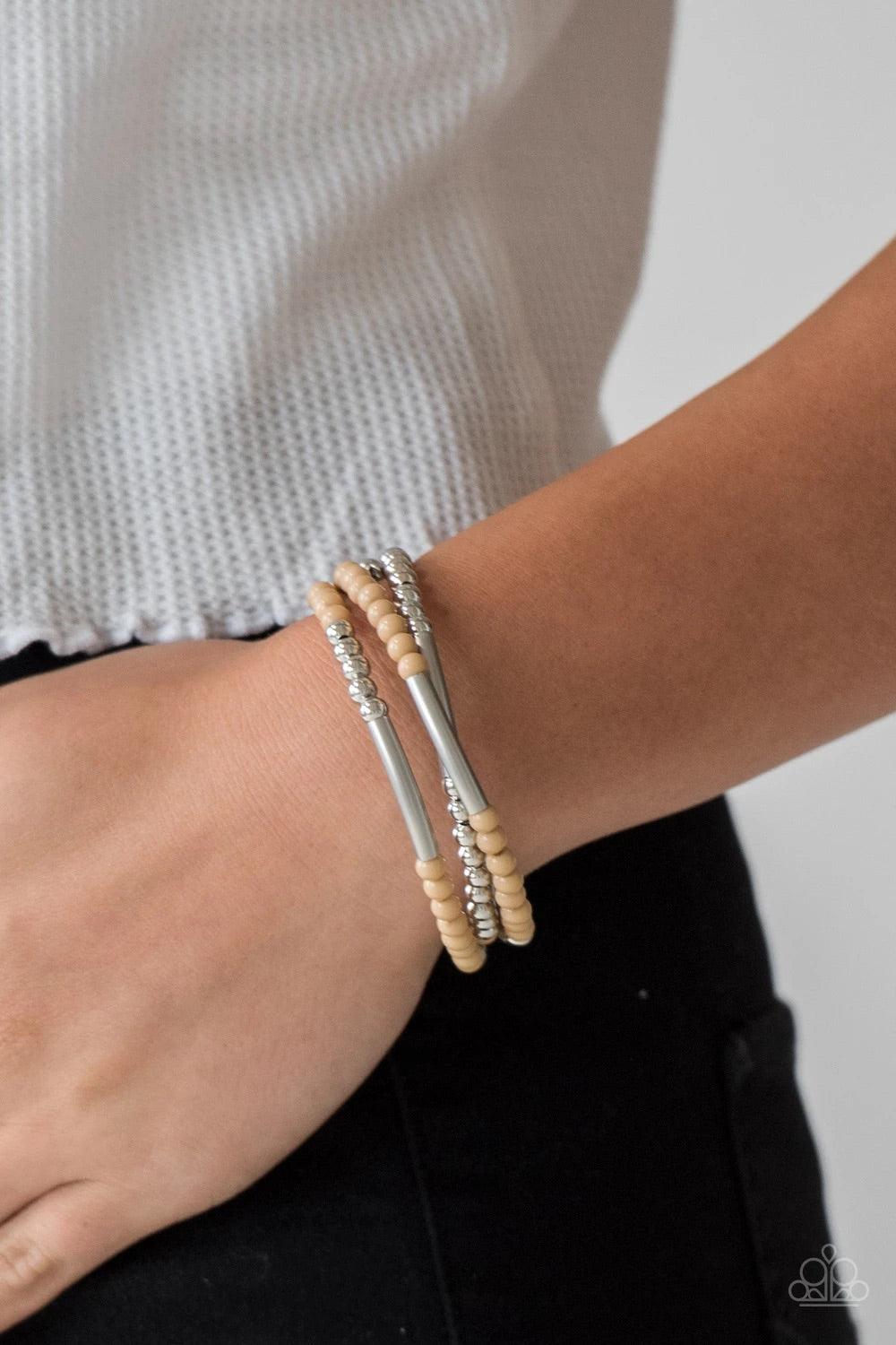 Paparazzi Accessories Tourist Trap - Brown A collection of neutral brown and shiny silver accents are threaded along a long wire to create an infinity wrap bracelet. Coil design allows for an adjustable fit. Sold as one individual bracelet. Jewelry