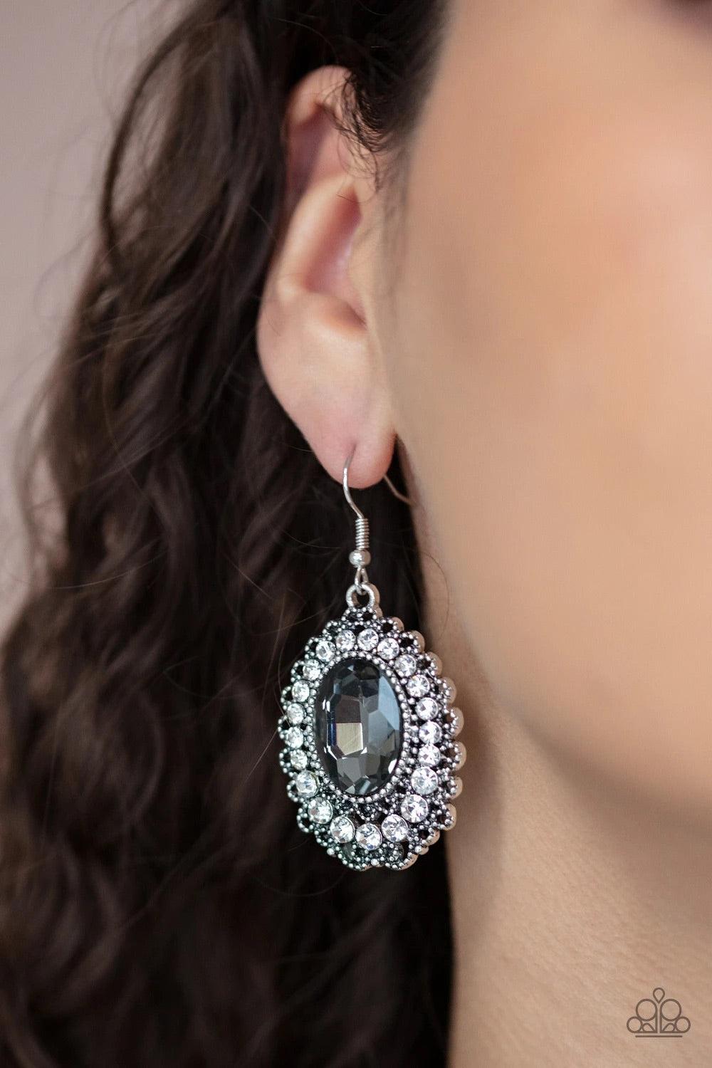 Paparazzi Accessories Glacial Gardens - Silver A smoky gem is pressed into the center of an ornately studded frame bordered in glassy white rhinestones, creating a glamorous statement piece. Earring attaches to a standard fishhook fitting. Sold as one pai