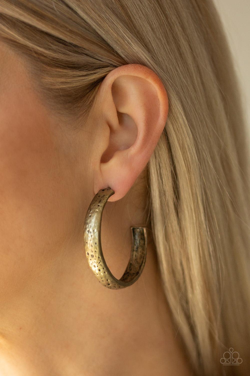 Paparazzi Accessories Rustic Revolution - Brass Featuring a hammered antiqued finish, a thick brass hoop curls around the ear for a trendy rustic look. Earring attaches to a standard post fitting. Hoop measures approximately 1 1/4" in diameter. Sold as on