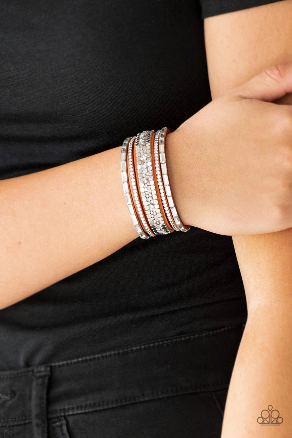 Paparazzi Accessories Rebel In Rhinestones - Orange Featuring round and emerald style cuts, glassy white rhinestones join flat silver cubes and metallic prism rhinestones along an orange suede band for a sassy look. Features an adjustable snap closure. So