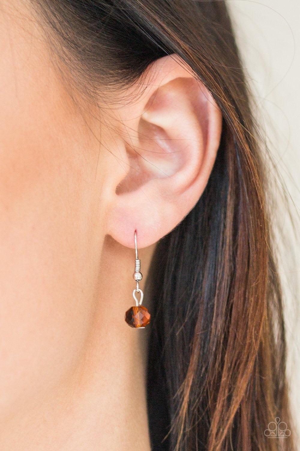 Paparazzi Accessories Socialite of the Season - Brown A glittery brown crystal-like bead swings from the bottom of a lengthened silver chain, giving way to a shimmering silver tassel for a glamorous finish. Features an adjustable clasp closure. Sold as on