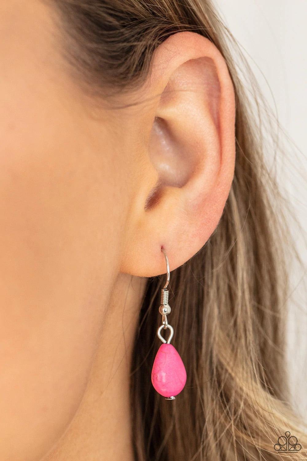 Paparazzi Accessories Tropical Mirage - Pink A silver feather, palm leaf, and dainty silver flower overlap atop an oversized pink stone teardrop that is nestled inside a textured scalloped frame, creating a dramatic pop of color at the bottom of a lengthe