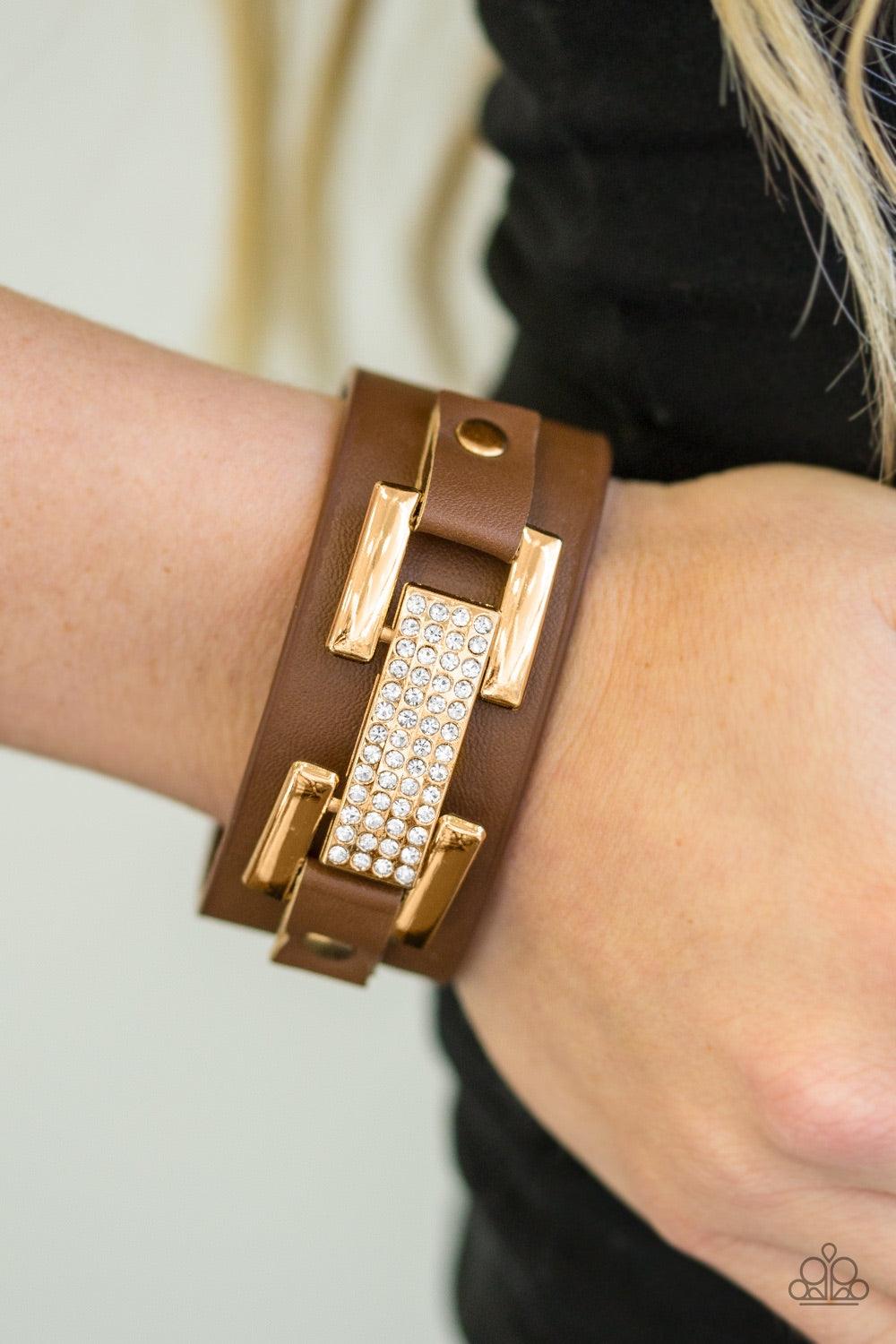 Paparazzi Accessories Going Platinum - Brown Encrusted in glittery white rhinestones, a glistening gold frame is studded in place across the front of a brown leather band for a glamorous look. Features an adjustable snap closure. Jewelry