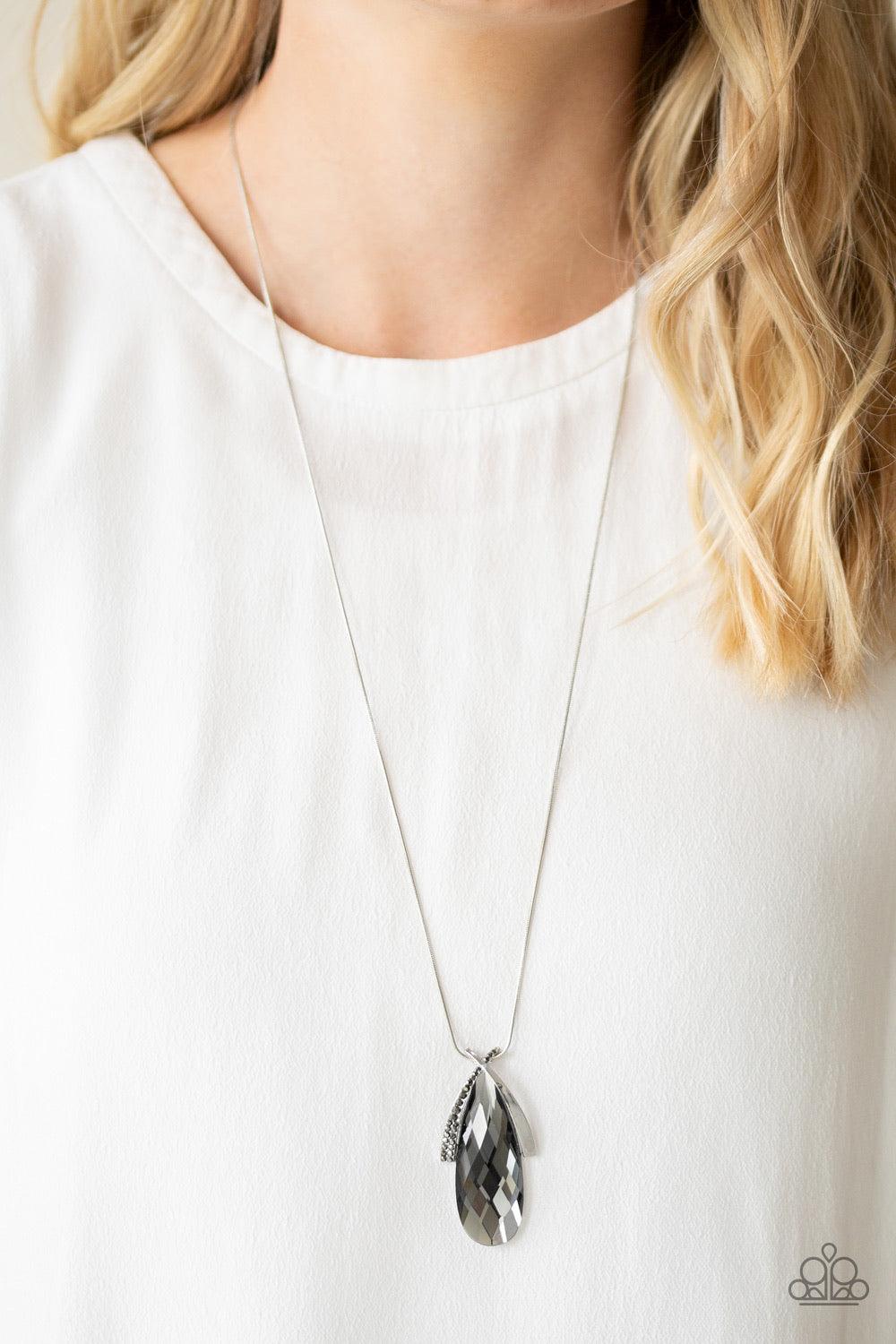 Paparazzi Accessories Stellar Sophistication - Silver A hematite rhinestone encrusted frame and smooth silver frame overlap at the top of a faceted smoky teardrop gem, creating a dramatic pendant. The refined pendant swings from the bottom of a rounded sn